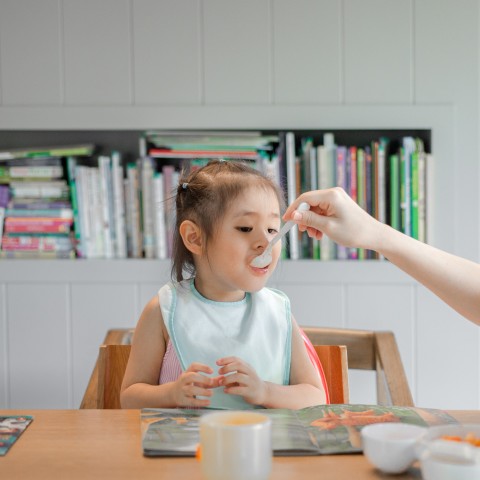 child being fed at table