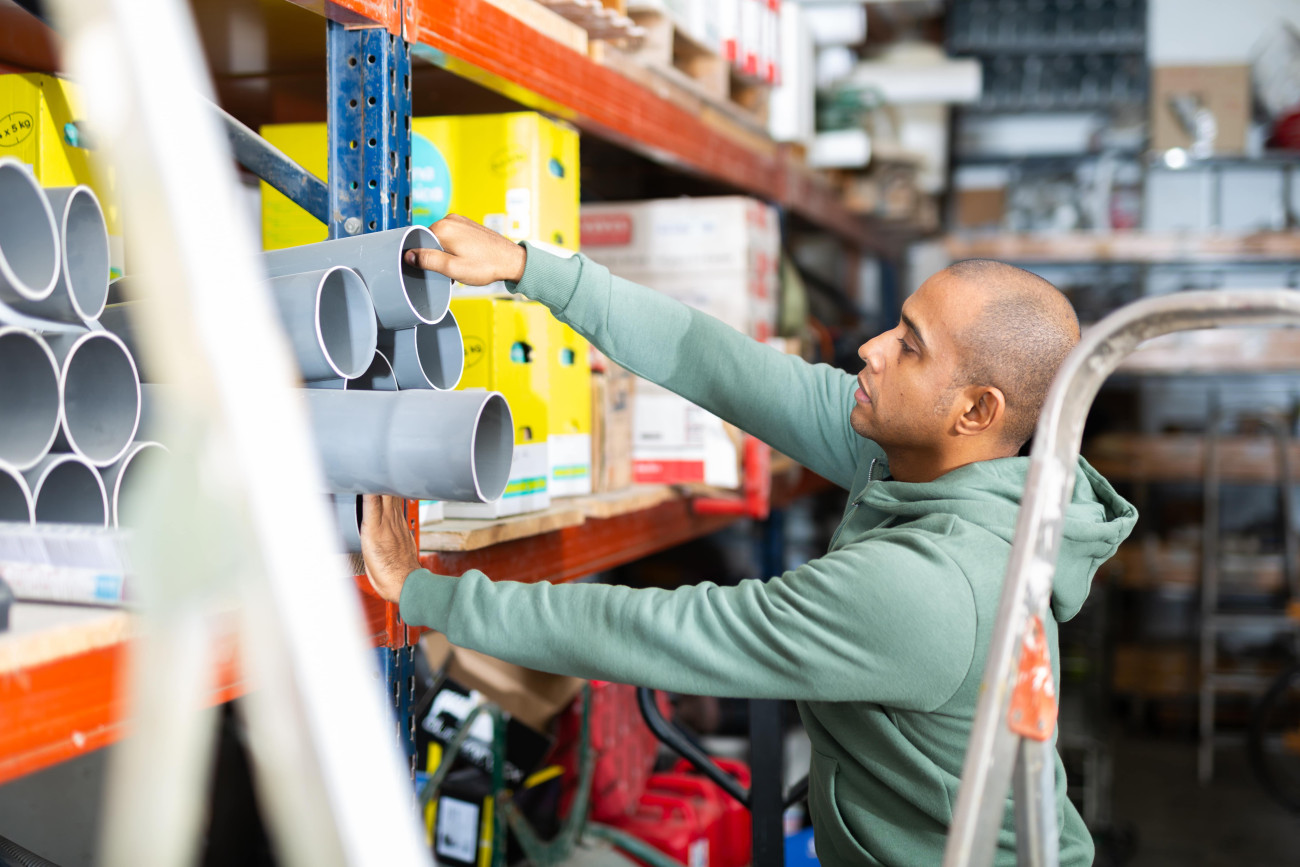 Side view of man standing and selecting a building material from a shelf